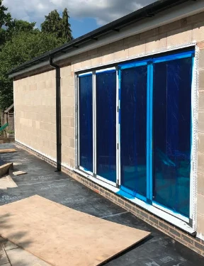 New render finish around bi-fold doors on a house extension, protective film still on the glass
